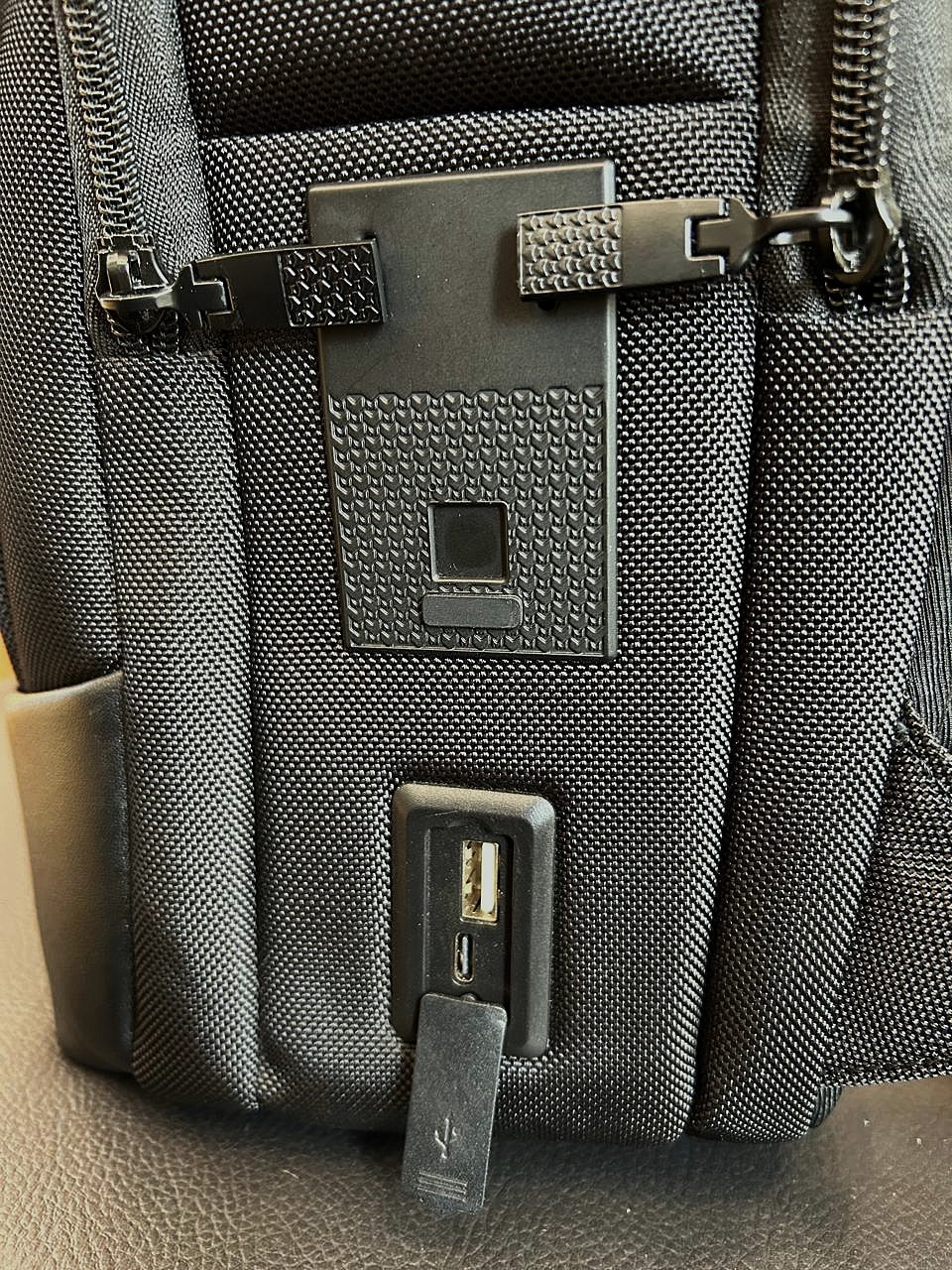Close-up of a gray backpack with a visible brand logo on a neutral background