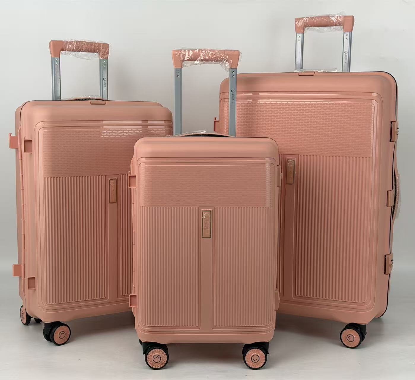 Three rose gold suitcases of different sizes on a light gray background
