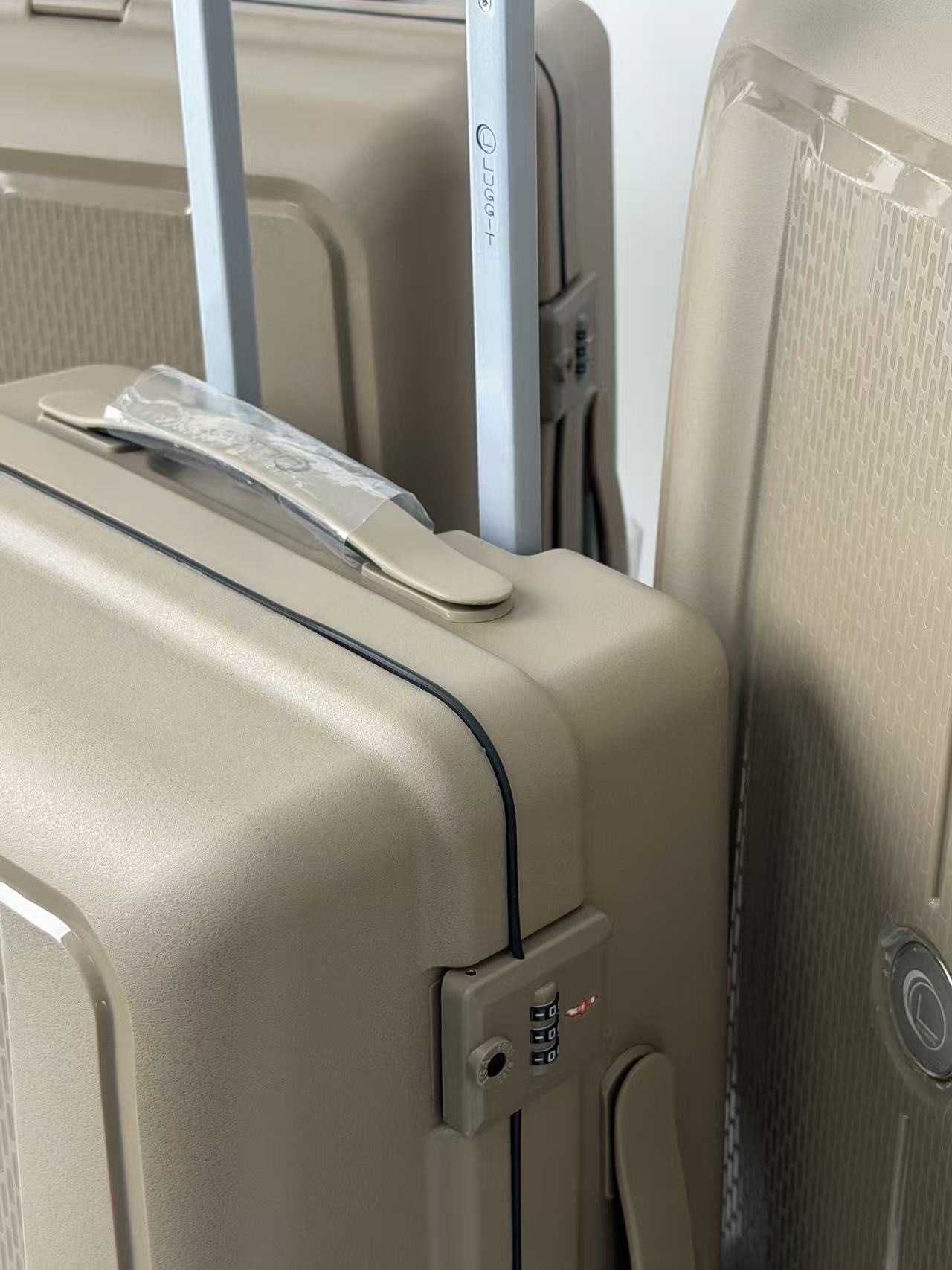 Close-up of beige suitcases with a focus on a suitcase handle and lock.